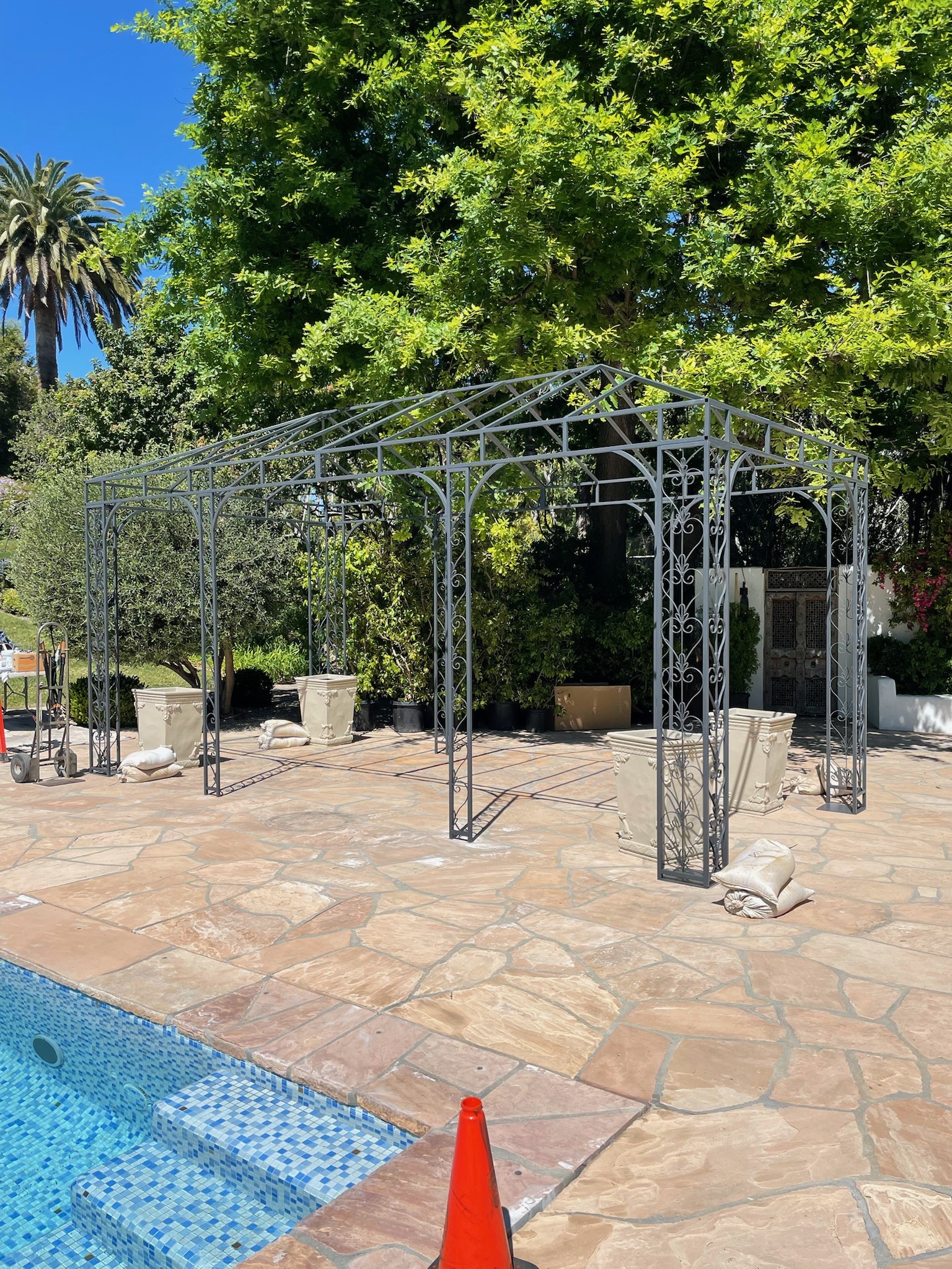 Structural-steel pergola beside a pool on a flagstone patio